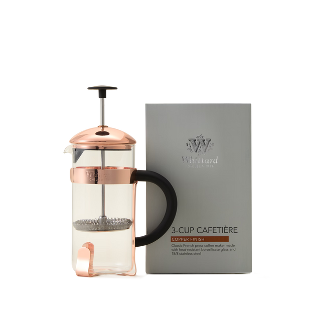 A Whittard Copper 3-Cup Cafetière, featuring a black handle, a durable borosilicate glass body, and a stainless steel filter, is placed next to its silver box labeled Whittard 3-Cup Cafetière.