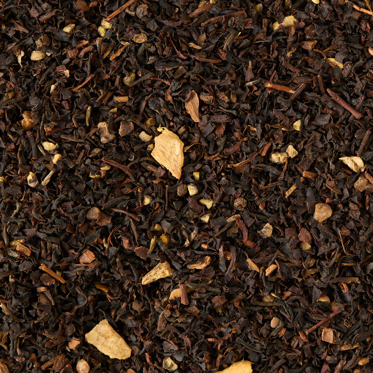 Spiced Chai Loose Leaf Tea is a textured blend of black tea, small pieces of dried ginger, cloves, and other spices, resulting in a dark brown and tan mix that is commonly used for making masala chai or other spiced tea blends.