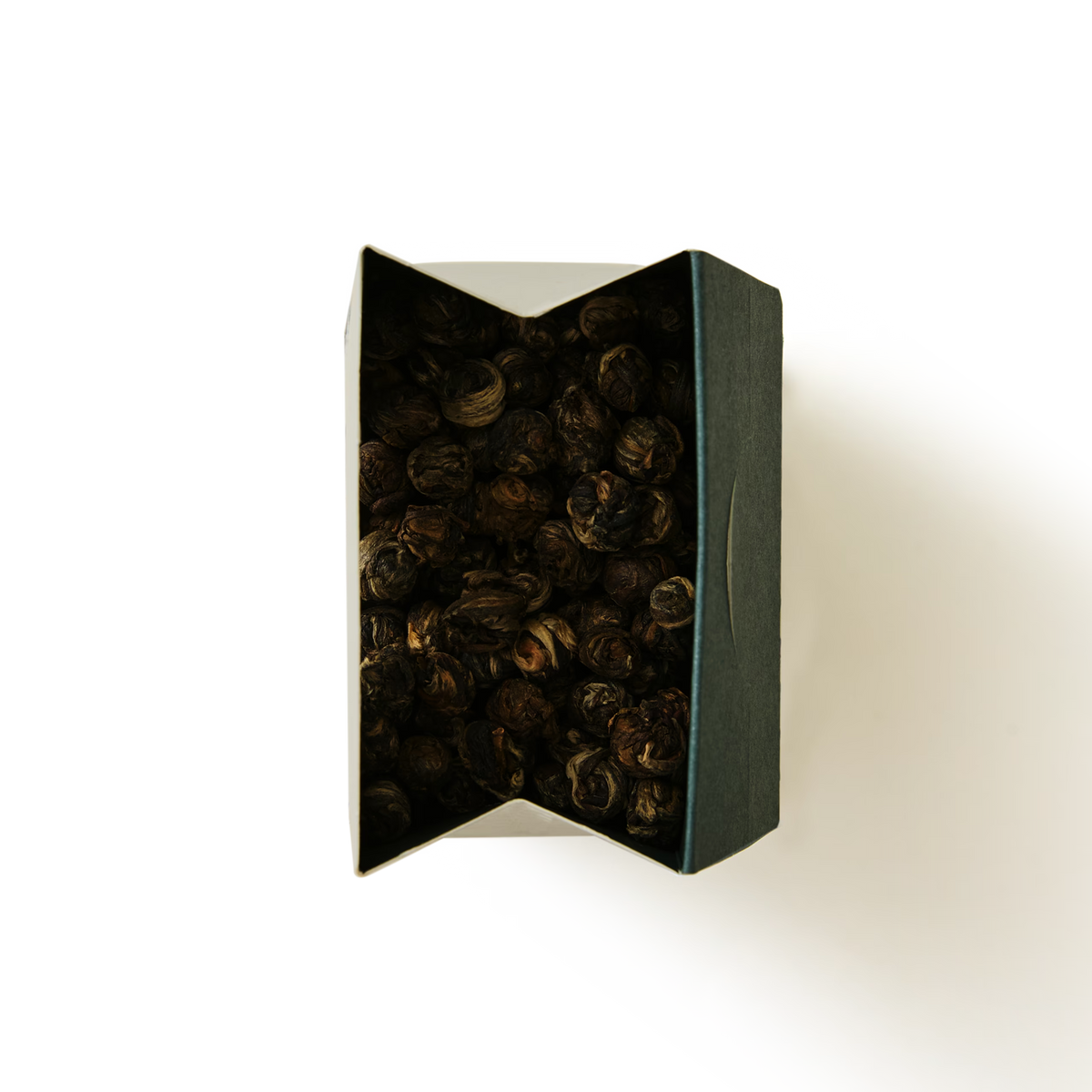 An open rectangular box filled with tightly rolled Jasmine Dragon Pearls Loose Leaf Tea leaves.