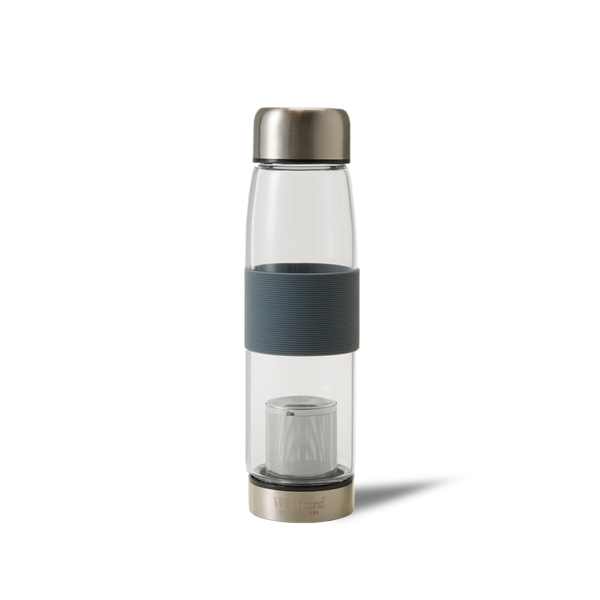 A clear glass water bottle with a metallic lid and base, a black textured grip in the middle, and a built-in infuser at the bottom. The background is plain white.
