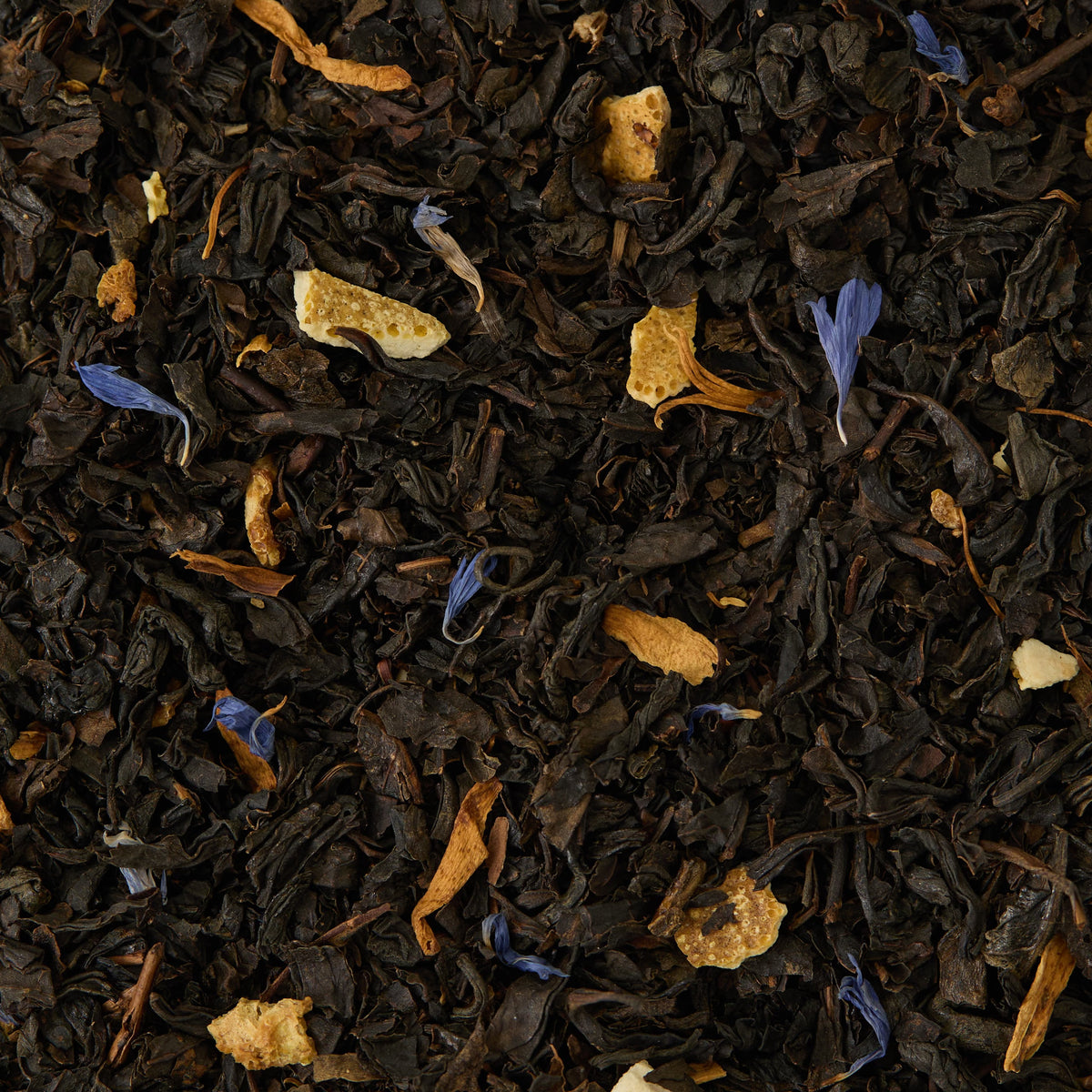 Loose leaf black tea blend with orange peel pieces and blue cornflower petals scattered throughout. The ingredients are shown in close-up detail.