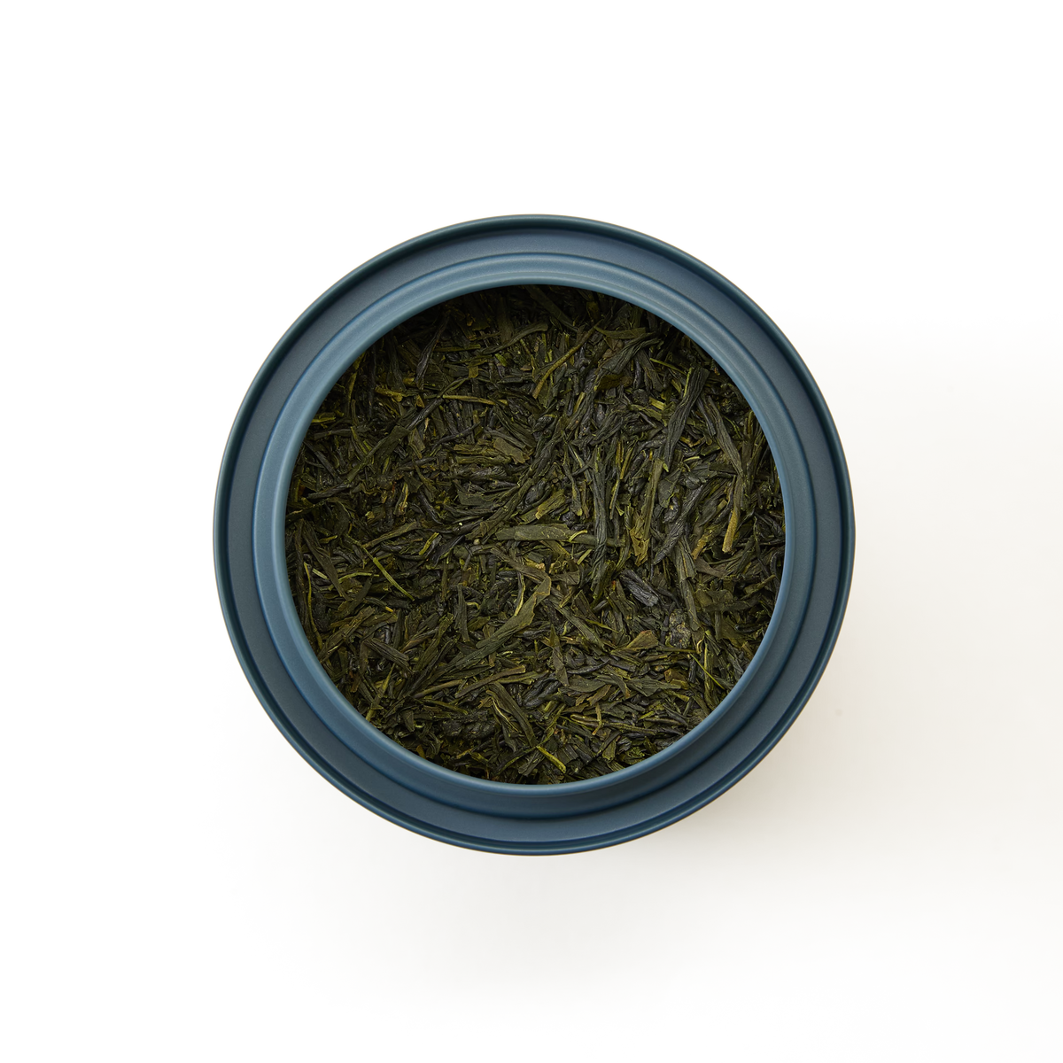 A blue container filled with loose Sencha Asagiri tea leaves viewed from above, set against a plain white background.