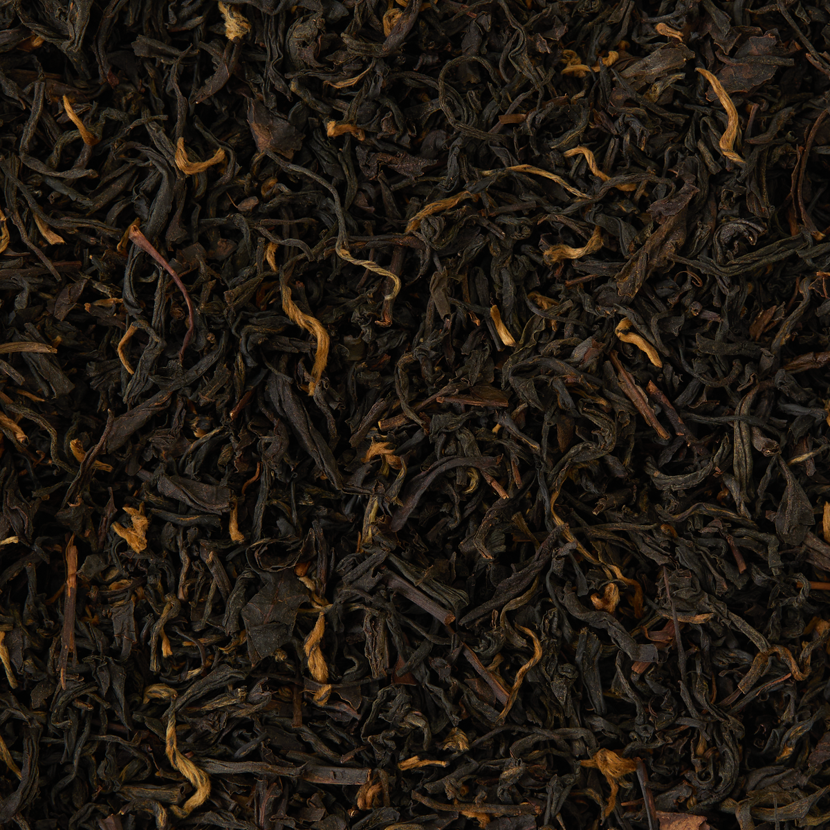A close-up view of Lapsang Souchong Loose Leaf Tea, displaying dark, twisted leaves with occasional golden tips, densely packed across the entire image and hinting at the distinctive smoky aroma characteristic of this tea.