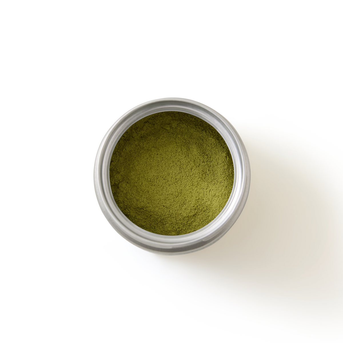 A round metal tin filled with fine green powder, viewed from above on a white background.