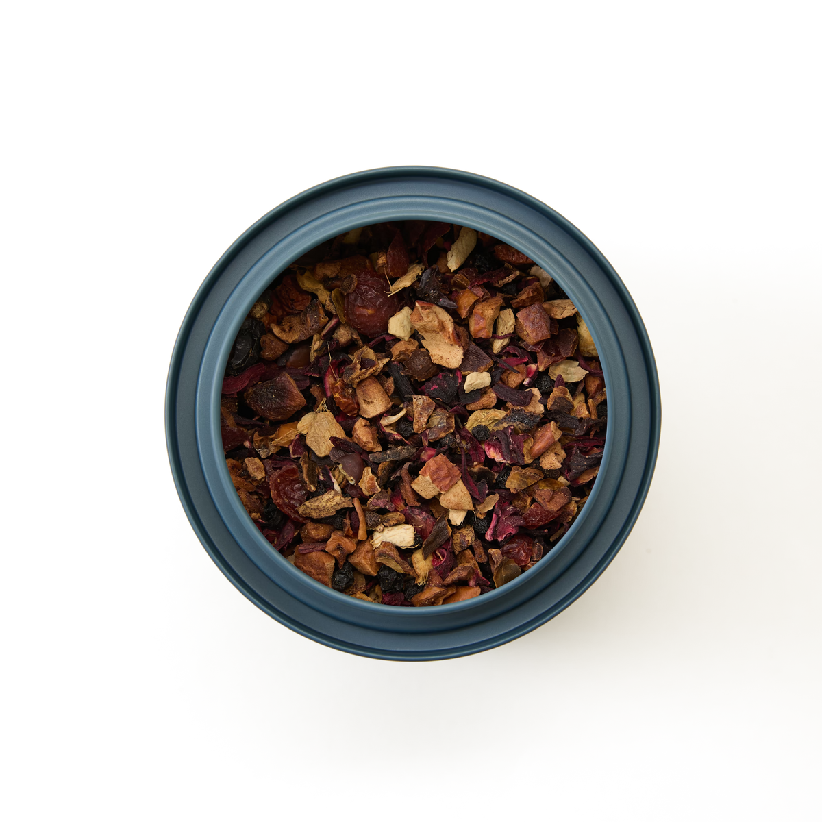 A round, dark container filled with Berry Elixir Loose Infusion—a dried fruit and herbal tea blend—viewed from above on a plain white background.