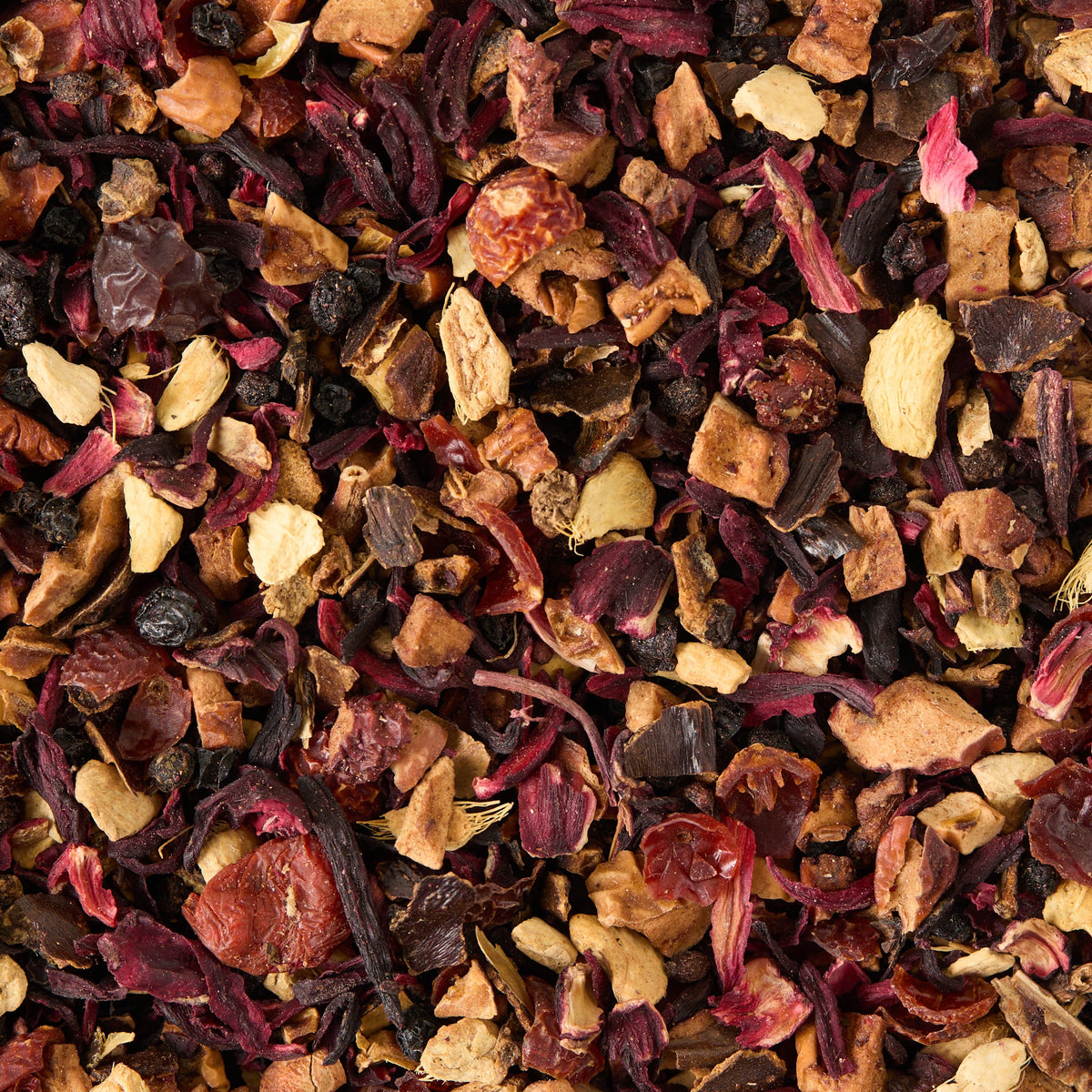 A close-up of Berry Elixir Loose Infusion—a vibrant herbal tea blend featuring visible pieces of apple, hibiscus, berries, elderberries, ginger, and other botanicals—perfect for a flavorful and inviting infusion.