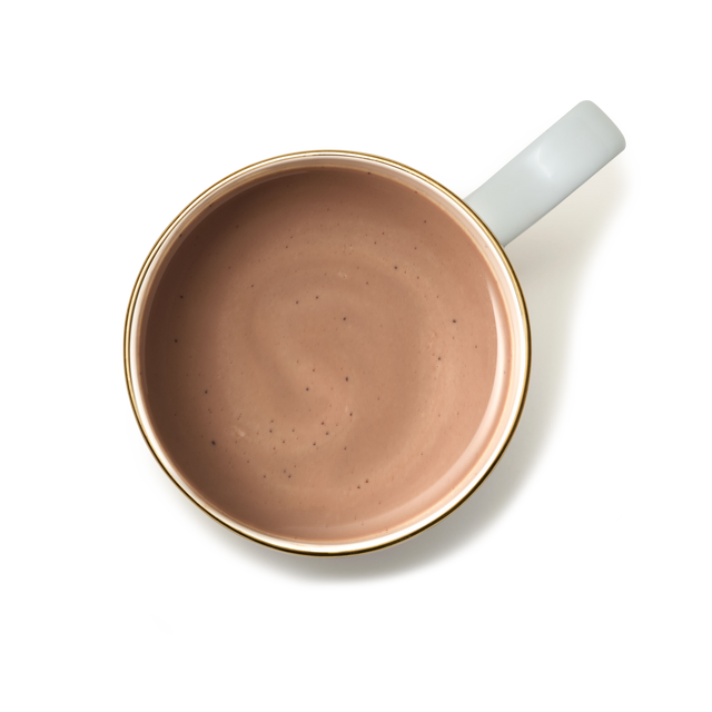 A top-down view of a white ceramic cup with a gold rim, filled with Luxury Hot Chocolate in a light brown hue, set against a plain white background.
