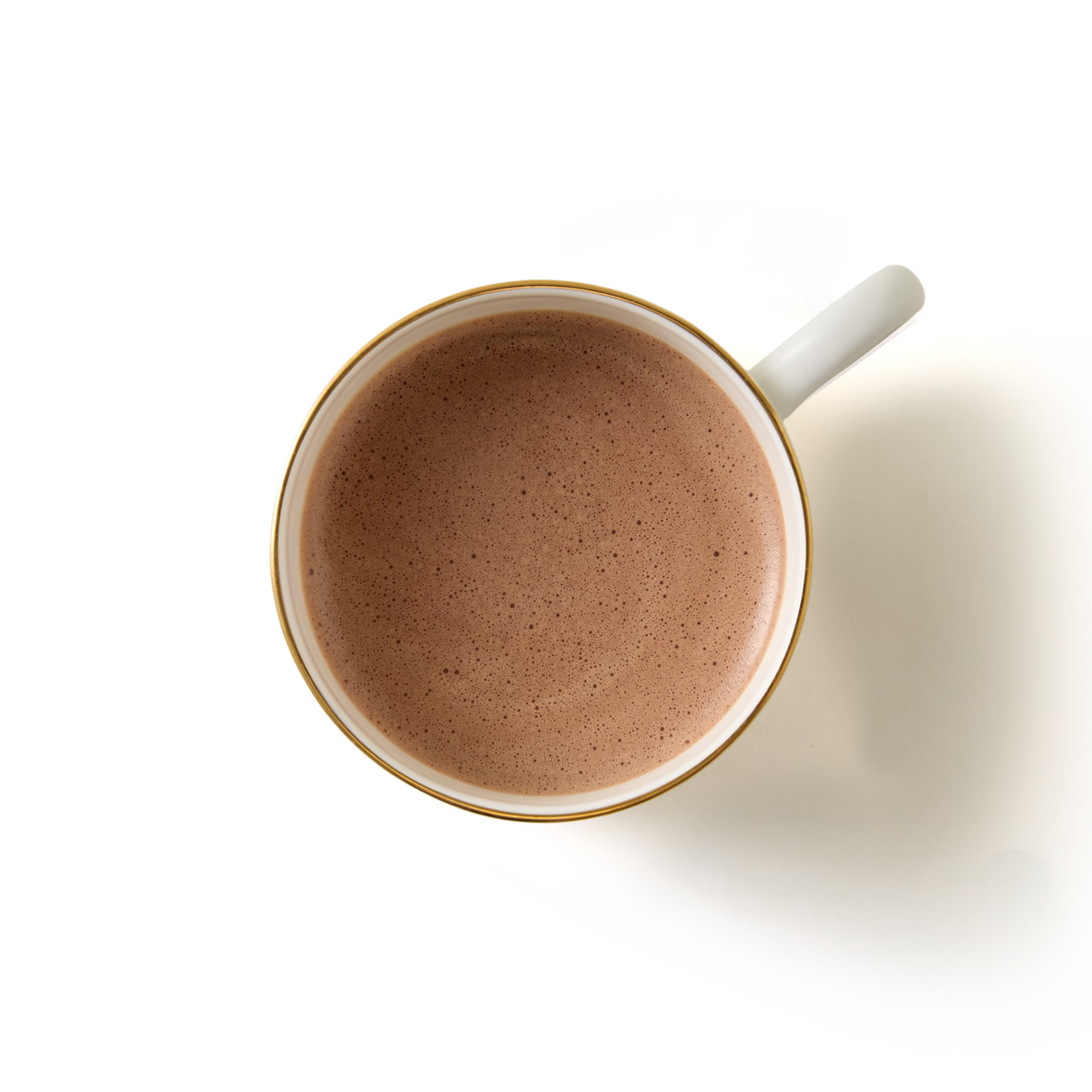 A top view of a white cup with a gold rim, filled with frothy Salted Caramel Flavour Hot Chocolate and a hint of sea salt, set against a white background.