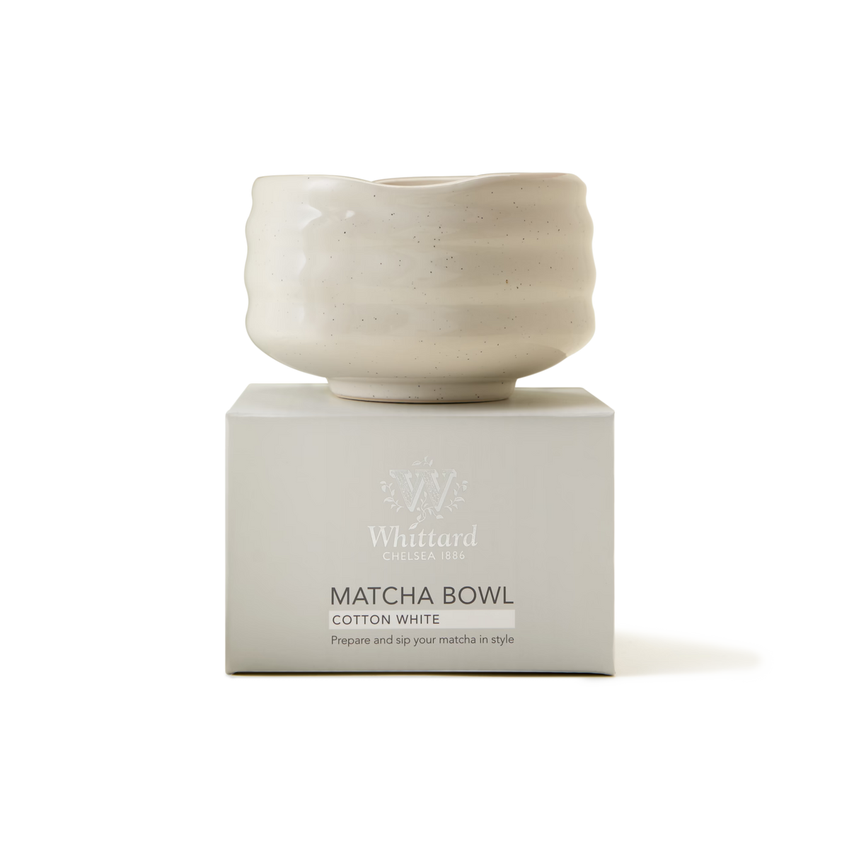 A white, wavy-edged matcha bowl sits atop a matching box labeled Whittard Matcha Bowl, Cotton White. The box also reads, Prepare and sip your matcha in style..