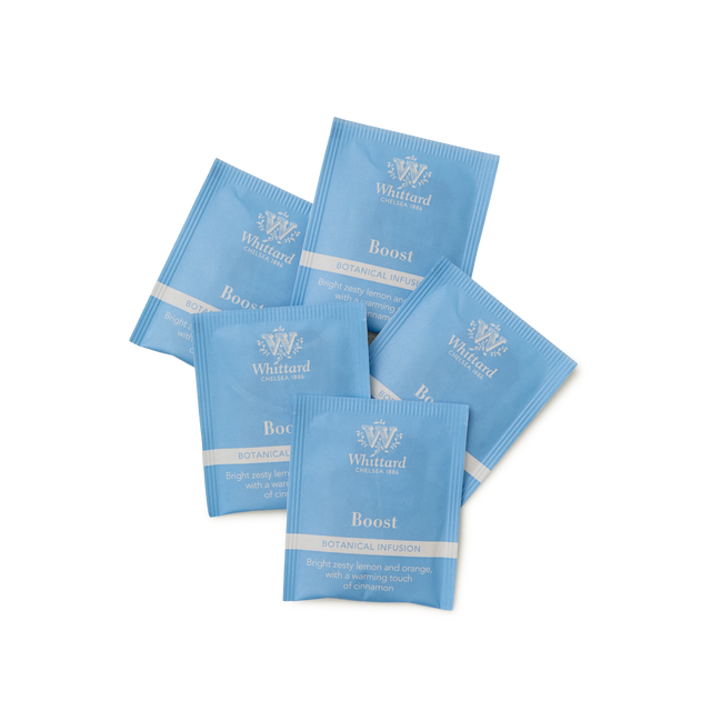 Five blue Whittard Boost Botanical Infusion tea sachets are arranged in a fan pattern on a white background. The sachets include details about the flavor: lemon and orange with comforting ginger.