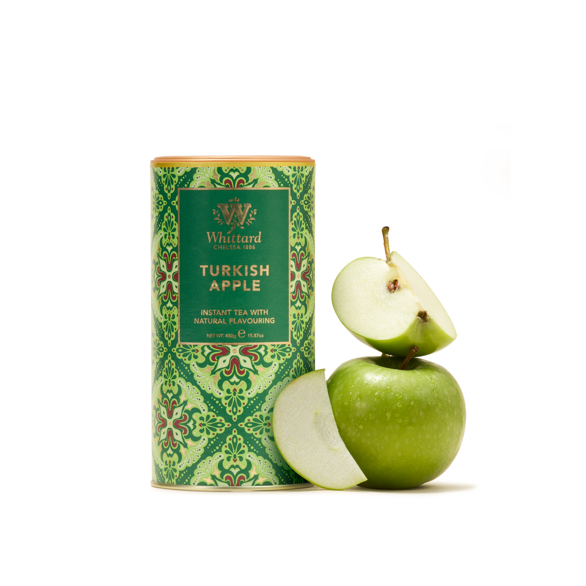 A green canister labeled “Turkish Apple Flavour Instant Tea” stands next to a green apple, sliced to reveal two wedges. The package showcases an ornate green and gold pattern that evokes the warmth and tradition of Turkish hospitality.