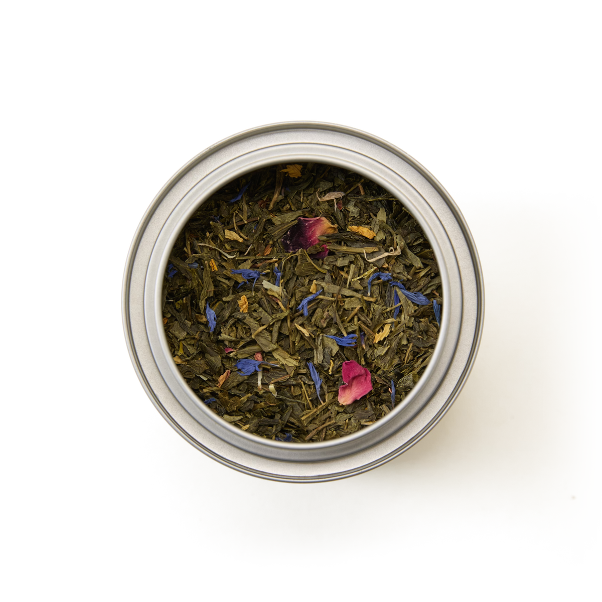 A round metal Tea Discoveries Mango & Bergamot Tea Caddy filled with loose leaf tea, viewed from above on a white background.