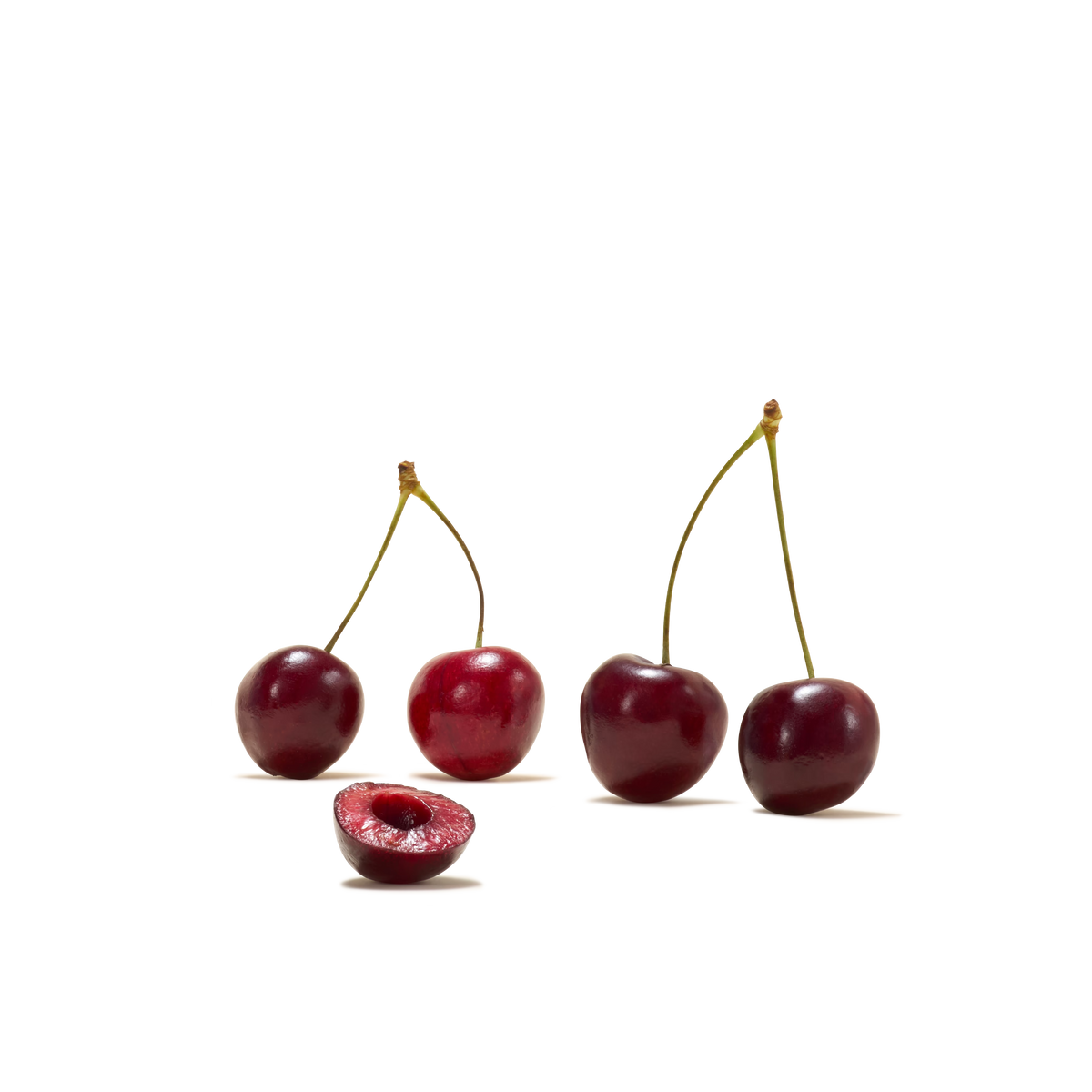 Four whole cherries with stems and one halved cherry revealing its pit, beautifully arranged on a white background—perfect inspiration for refreshing drinks like Sour Cherry Instant Tea.