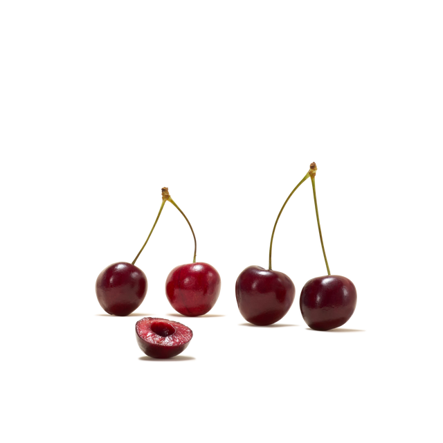 Four whole cherries with stems and one halved cherry revealing its pit, beautifully arranged on a white background—perfect inspiration for refreshing drinks like Sour Cherry Instant Tea.