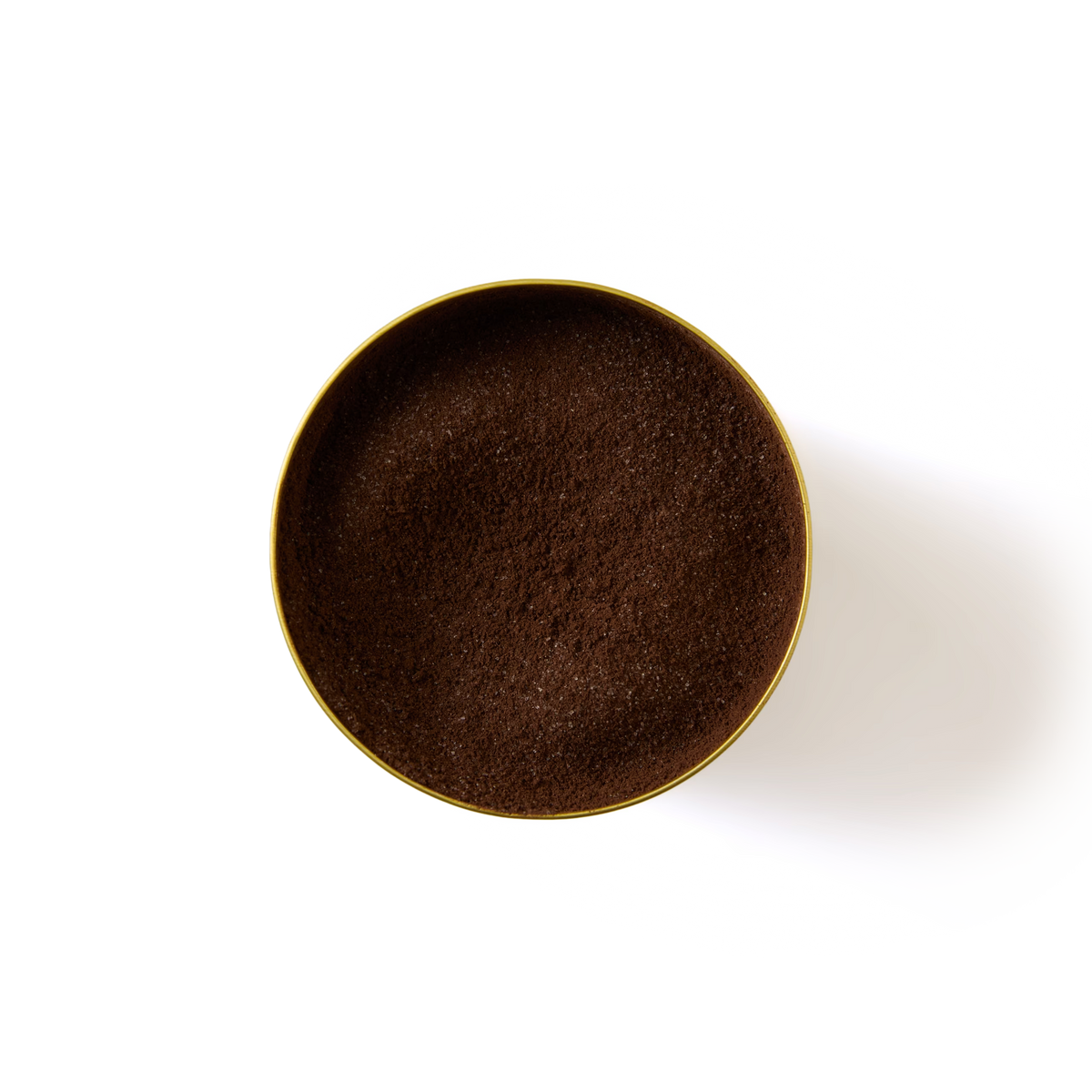 A round, gold tin filled to the top with finely ground dark cookies and cream flavour hot chocolate, viewed from above against a white background.