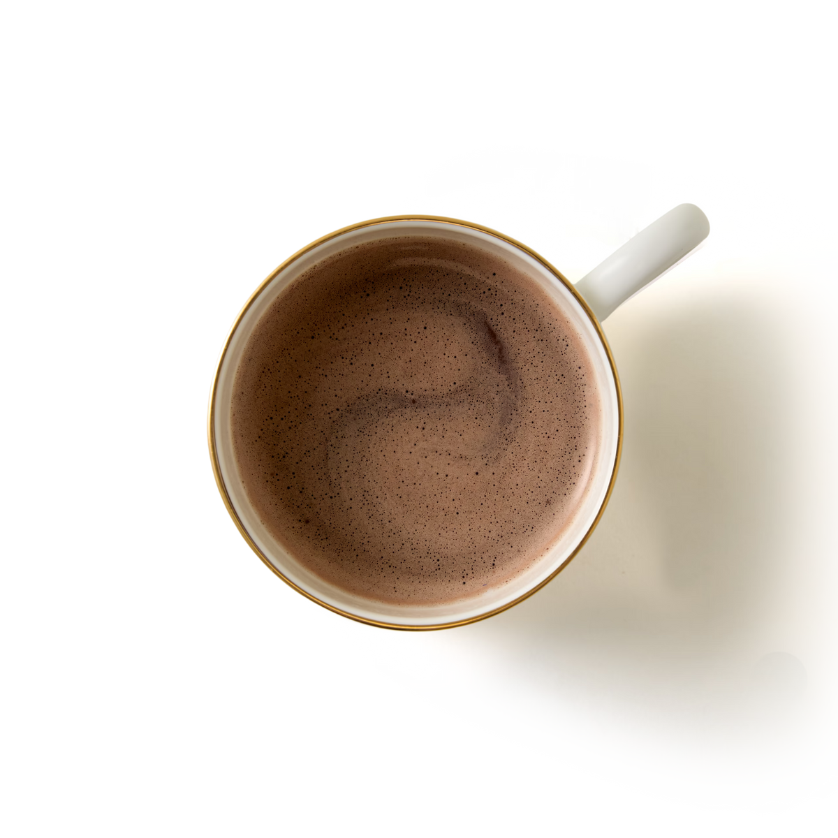 A top-down view of a white mug filled with Cookies and Cream Flavour Hot Chocolate, featuring a light swirl on the frothy surface and set against a plain white background—highlighting the rich, indulgent notes characteristic of cookies and cream.