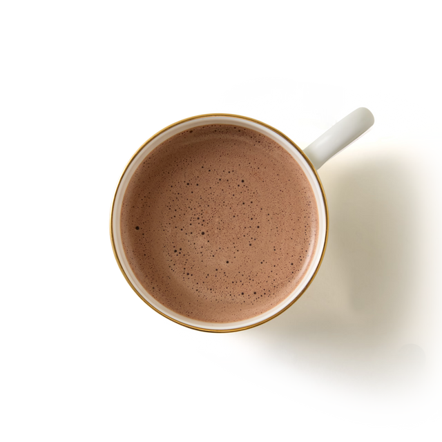 Top view of a white mug filled with frothy 70% Cocoa Hot Chocolate, placed on a white background.