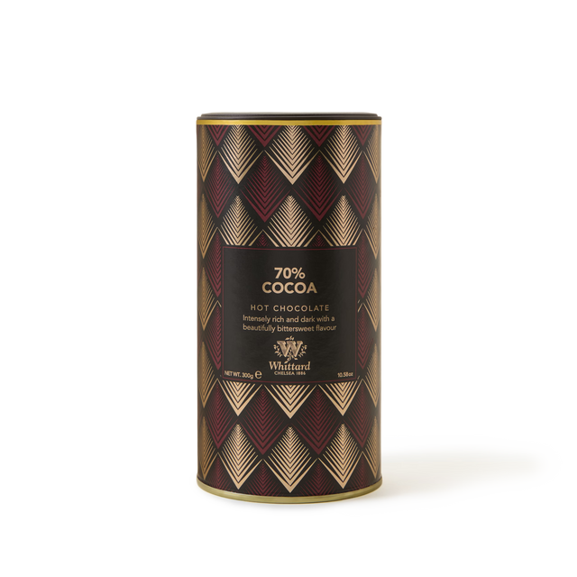 A cylindrical tin of Whittard 70% Cocoa Hot Chocolate with a geometric red, gold, and black pattern. The label describes it as rich and dark with a bittersweet flavor.