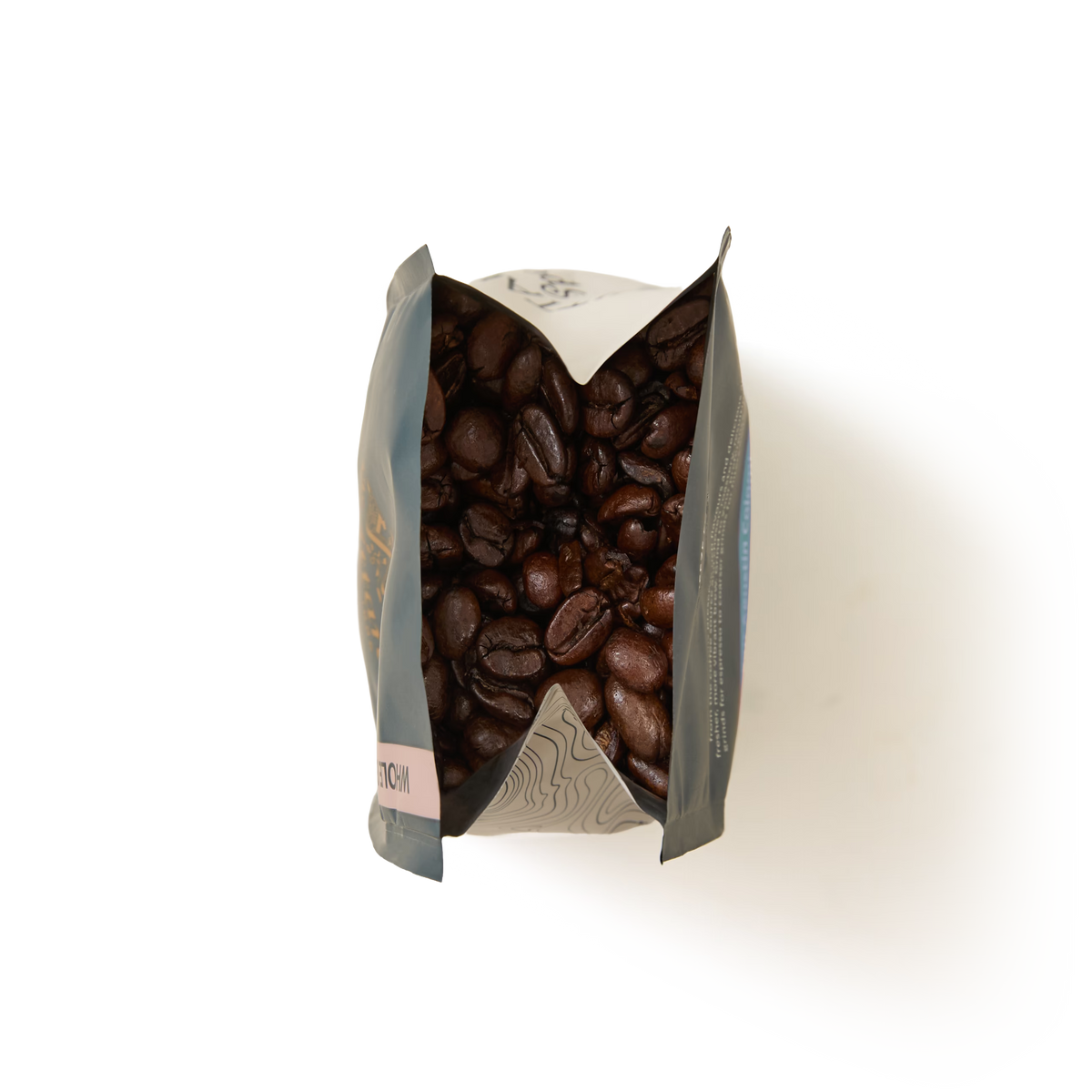 A top-down view of an open Santos and Java Coffee Beans Valve Pack filled with dark roasted coffee beans, set against a plain white background.