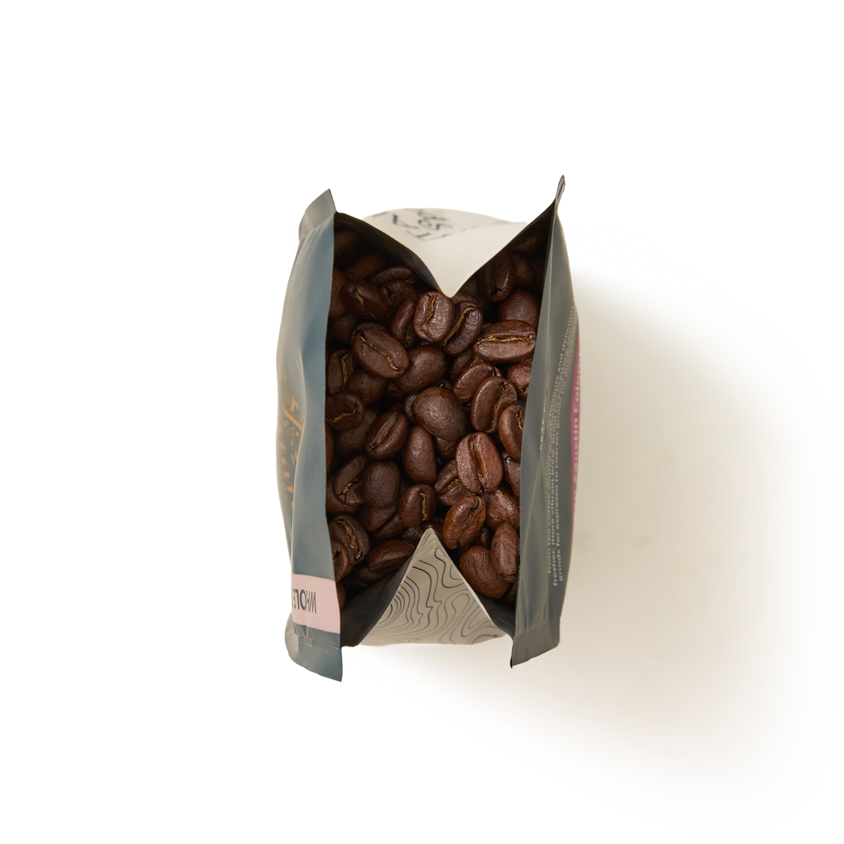 A top-down view of an open San Agustin Colombia Coffee Beans Valve Pack filled with roasted coffee beans, with the bag’s sides folded outward, on a plain white background.
