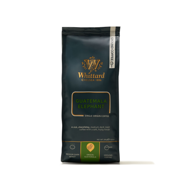 A 200g bag of Whittard Guatemala Elephant Ground Coffee Valve Pack, made from large coffee beans cultivated near Lake Atitlán, featuring gold and green labeling. The packaging displays medium dark roast icons and product details on a dark background.