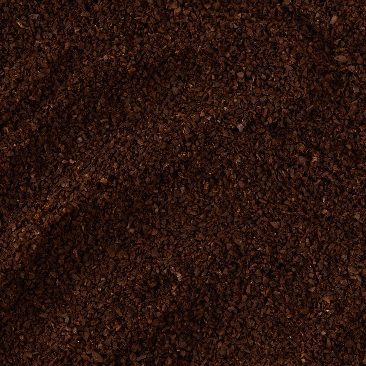 A close-up of a pile of dark brown San Agustin Colombia Ground Coffee Valve Pack grounds, highlighting their coarse texture and uneven granules.