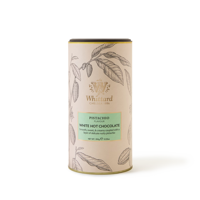 A cylindrical tin of Pistachio Flavour White Hot Chocolate, featuring botanical illustrations on a cream background and a green label showcasing the product details—a luxurious white chocolate drink delicately infused with pistachio flavour.