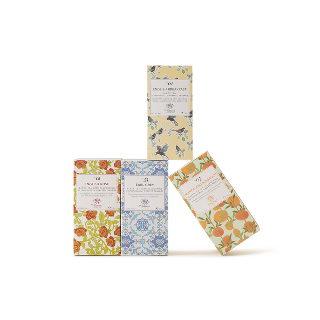 Four boxes of tea with decorative floral patterns in different colors are arranged on a white background; three boxes stand upright, and one leans against the group. Each box features a white label with text.
