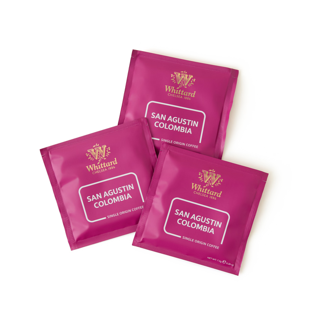 Three magenta packets of San Agustin Colombia Coffee Bags are arranged on a white background. Each compostable coffee bag displays the brand logo and coffee details in white text.