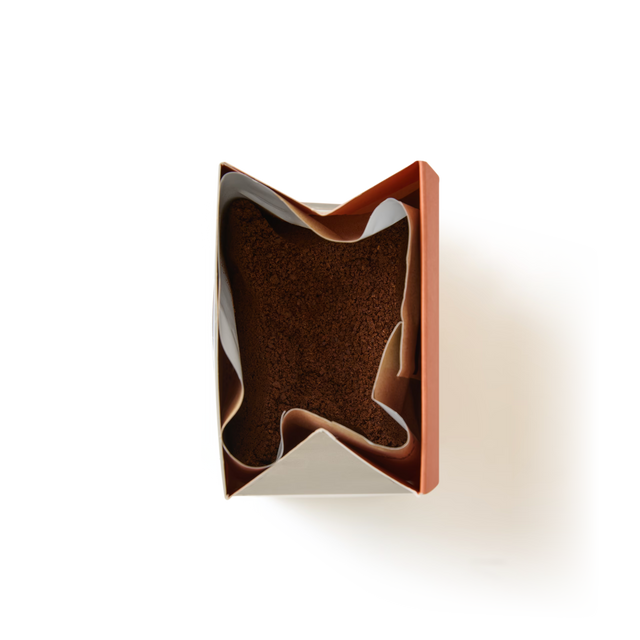 A rectangular box of Salted Caramel Flavoured Ground Coffee is partially wrapped in white parchment paper and viewed from above against a plain white background.