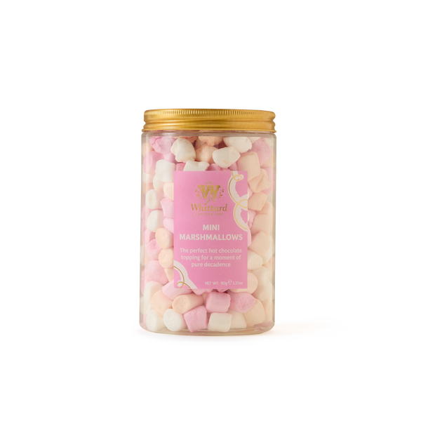 A clear jar with a gold lid is filled with Mini Marshmallows in pink and white, each infused with natural vanilla. Perfect for topping your hot chocolate, these delightful treats come in a jar featuring a pink and gold label that reads “Mini Marshmallows.”.