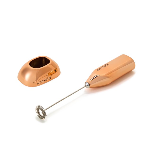 A rose gold handheld milk frother with a matching stand, both labeled aerolatte, positioned on a white background.