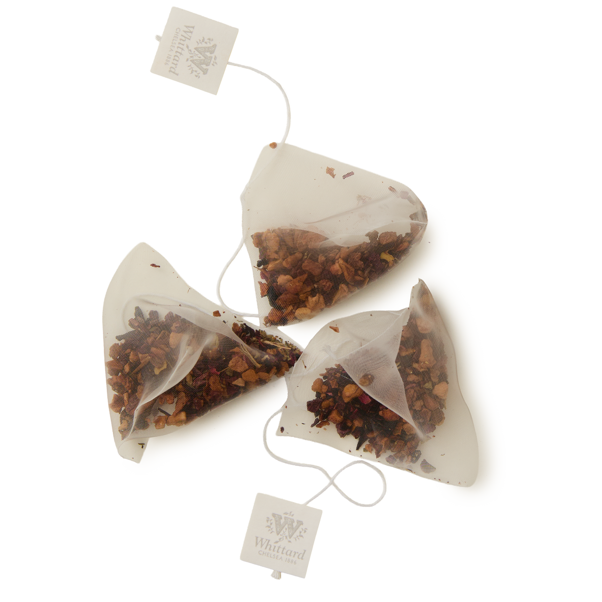 Three pyramid-shaped mesh teabags of Cold Brew Cherry & Mandarin Flavoured Infusion, each filled with loose tea leaves and fruit pieces and featuring a white string with a branded tag, are arranged on a white background—perfect for preparing a refreshing caffeine-free drink.