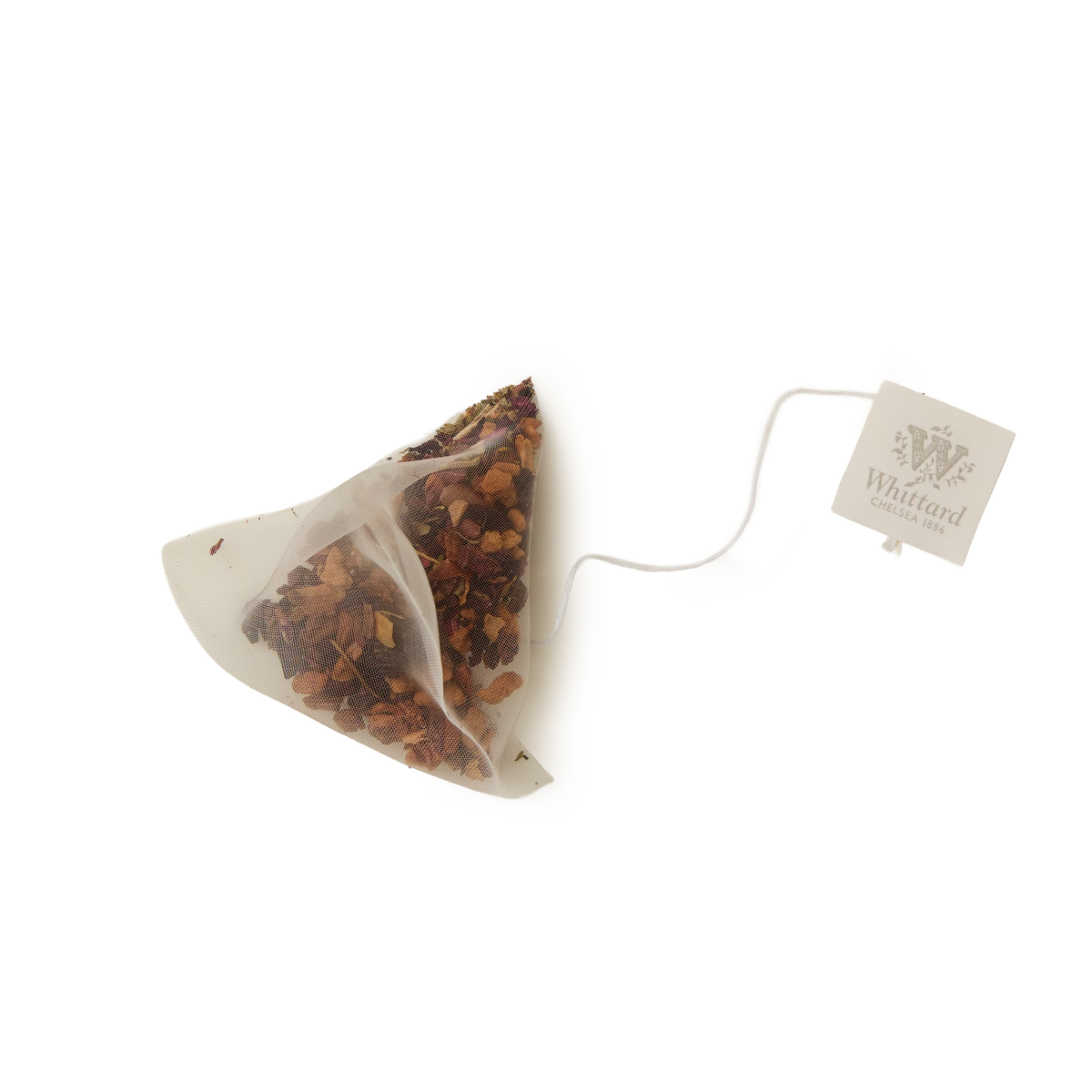 A pyramid-shaped tea bag from Whittard’s Cold Brew Cherry & Mandarin Flavoured Infusion collection is filled with loose tea leaves and fruit pieces, perfect for a refreshing, caffeine-free cold brew. Attached to a string and a square tag labeled Whittard, the teabag is set against a plain white background.