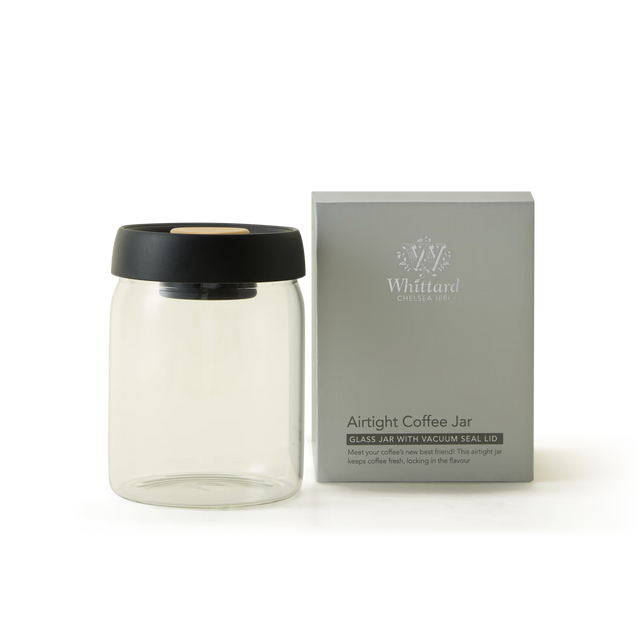 A clear airtight coffee jar with a black lid sits next to its gray Whittard-branded box, which reads Airtight Coffee Jar - Glass Jar with Vacuum Seal Lid..