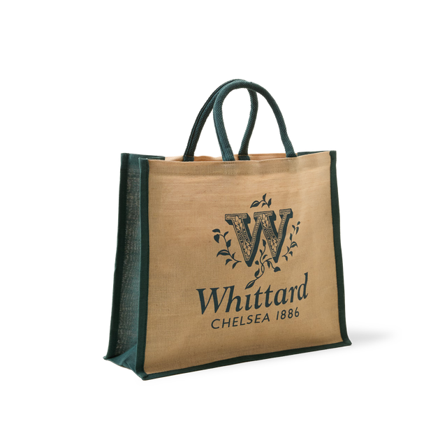 Introducing the Whittard Medium Jute Cotton Bag—a reusable shopping bag made from sturdy jute and cotton, complete with green handles and edges. This stylish bag showcases the Whittard Chelsea 1886 logo and a large decorative “W” on the front, making it perfect for everyday use.
