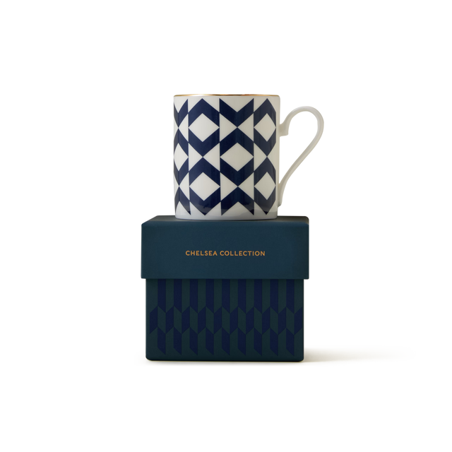 The Regency Espresso Cup rests atop a dark blue box adorned with subtle geometric designs and “CHELSEA COLLECTION” written in gold text. Hand-finished in England, this ceramic espresso cup displays a sophisticated blue and white geometric pattern accented with elegant 22ct gold detailing.