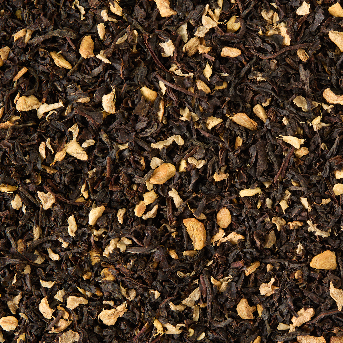 A close-up of Ginger Chai Loose Leaf Tea displays a textured and colorful blend of loose black tea leaves and small, dried ginger pieces—perfect for those seeking a winter warmer or a soothing cup of loose leaf chai.