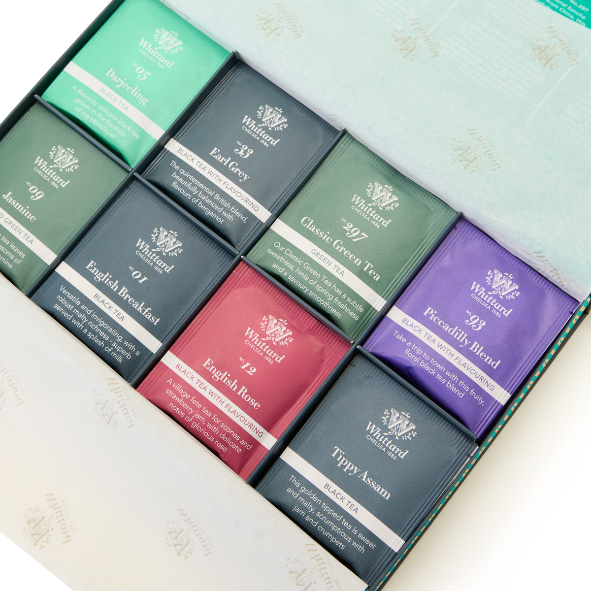 An open box reveals The Tea Explorer, a delightful collection featuring nine assorted Whittard of Chelsea tea sachets in a variety of colors and flavors such as Jasmine, Earl Grey, English Breakfast, Piccadilly Blend, Classic Green Tea, English Rose, and Tippy Assam. This exquisite selection offers an array of fine teas to suit every palate.