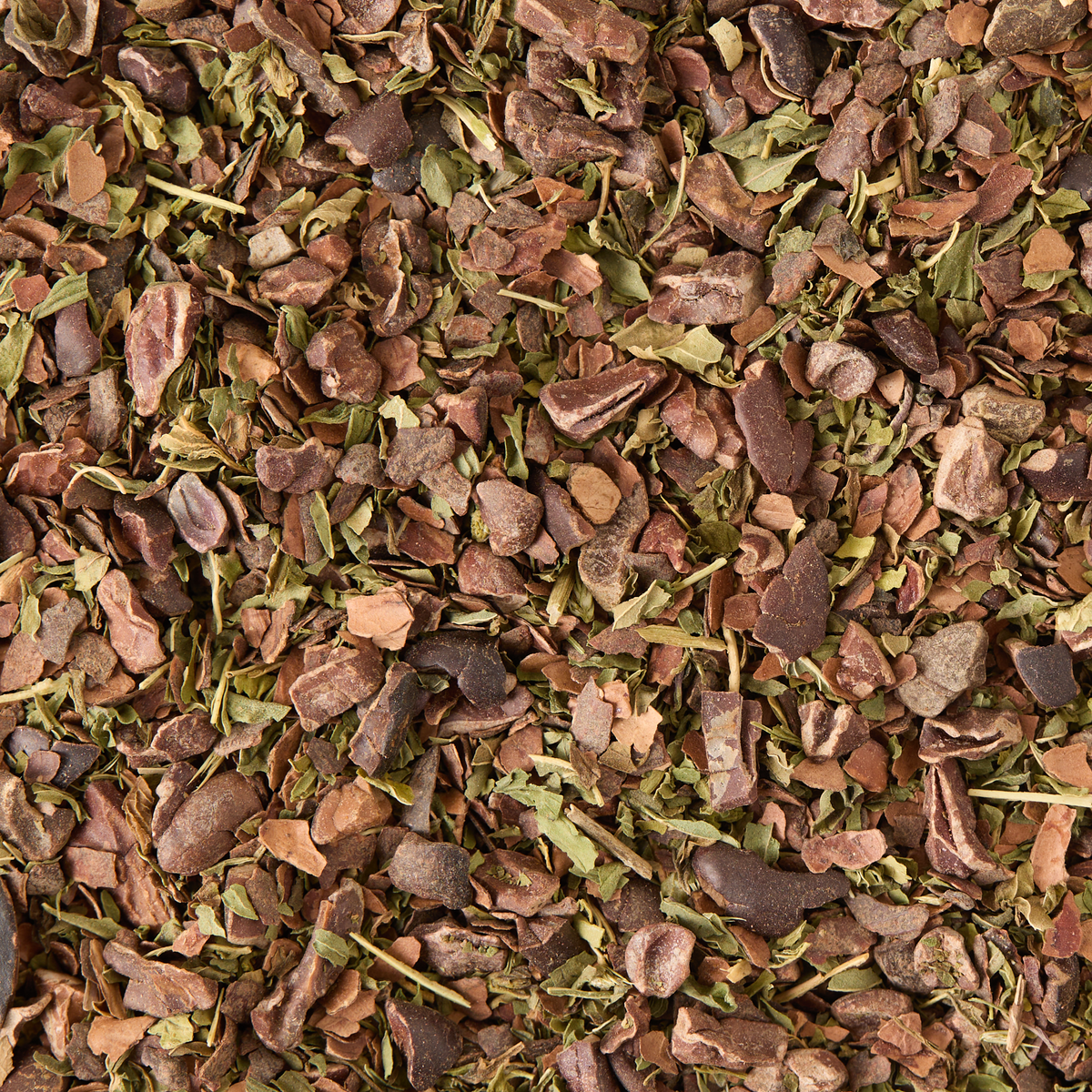 A close-up view of Cacao & Mint Loose Infusion, featuring a textured blend of dried brown and green herbs and plant leaves with various small pieces and fragments.