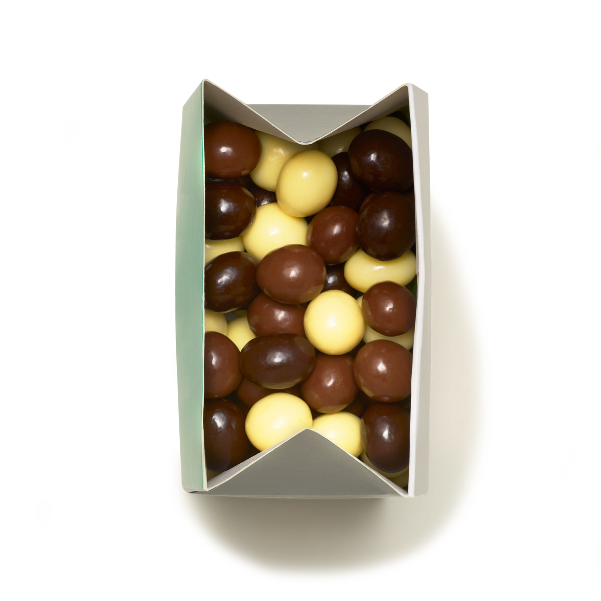 A rectangular box filled with Milk, Dark & White Chocolate Coated Espresso Beans in brown and yellow hues, viewed from above on a white background.