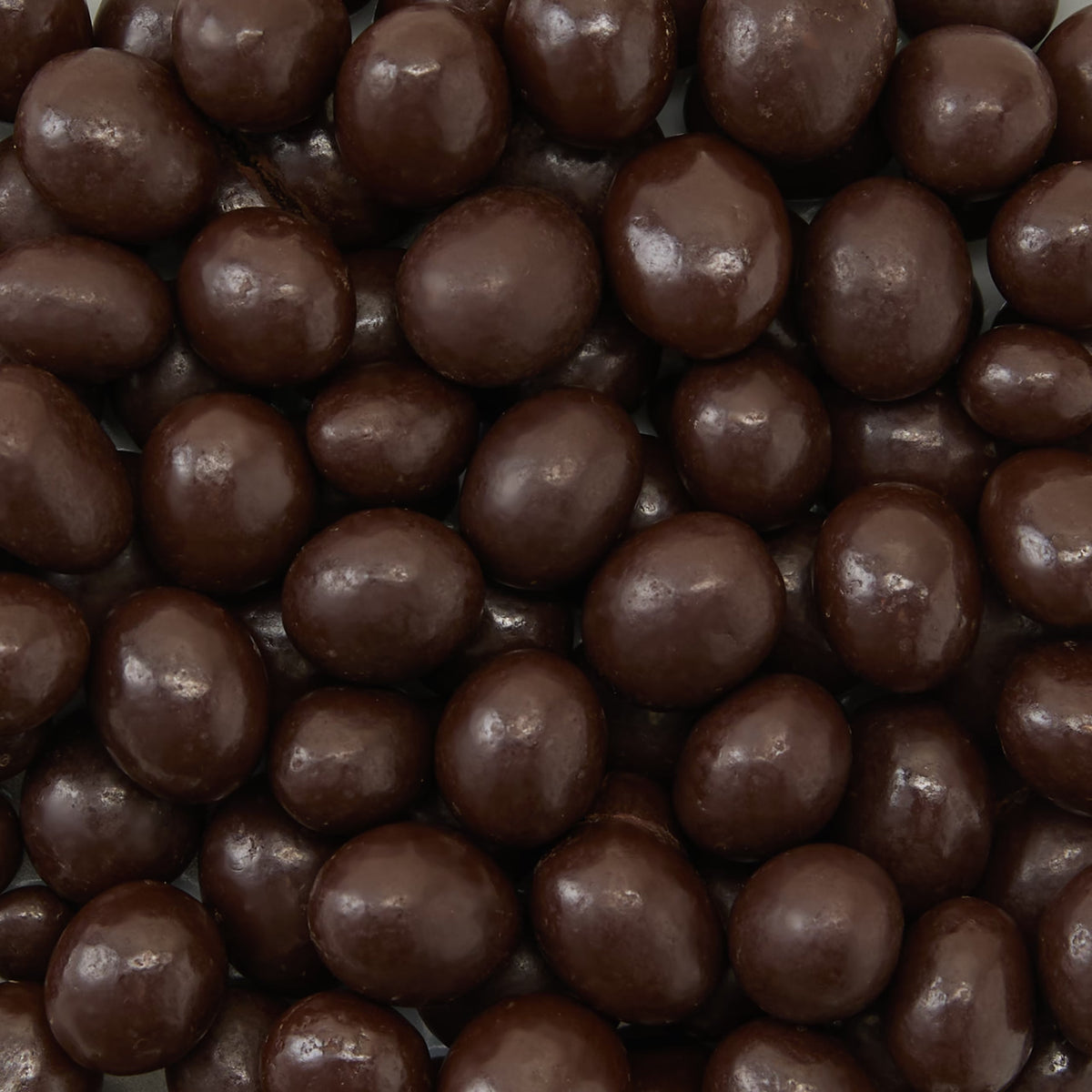 A close-up of many Dark Chocolate Coated Espresso Beans, highlighting their glossy, smooth, dark brown coating tightly packed together—a tempting treat sure to delight chocolate and coffee lovers.