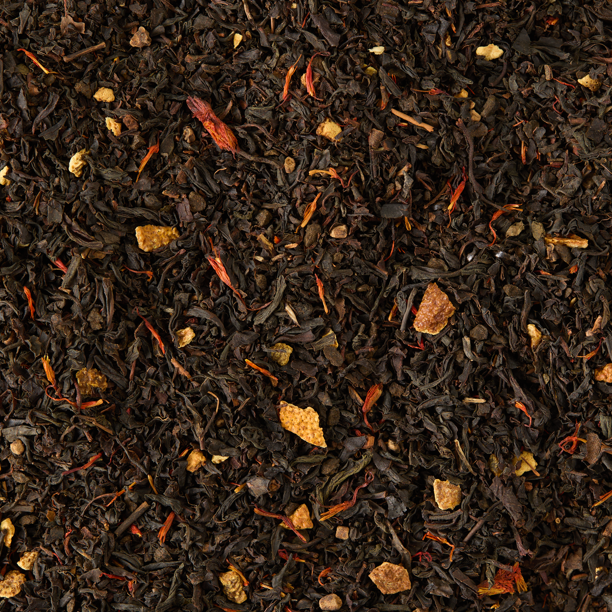 Christmas Tea Clip Top Tin is a loose leaf black tea blend featuring dried orange peel, ginger pieces, and scattered safflower petals, creating a visually textured mix of dark brown, light tan, and red-orange hues.