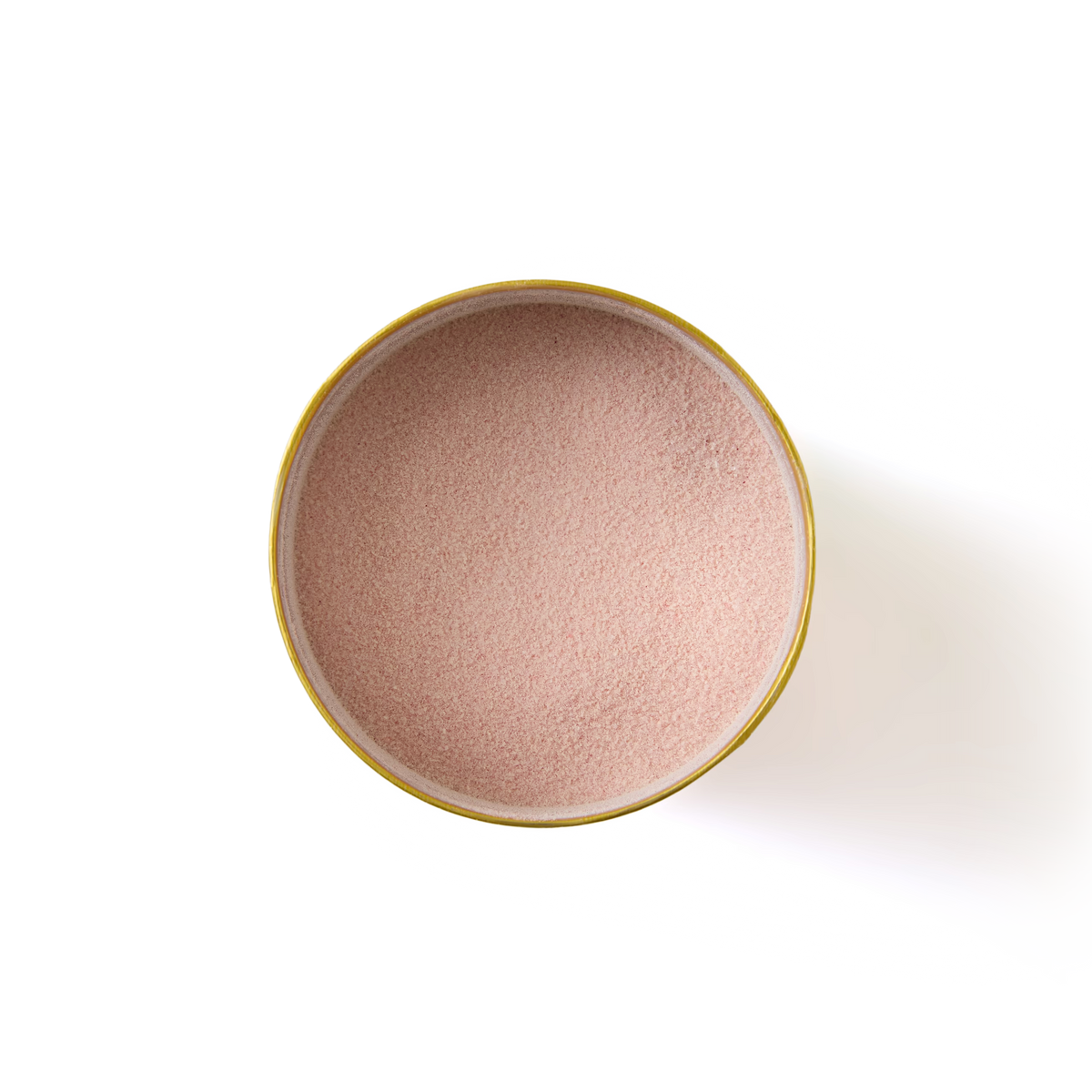 A round yellow bowl filled with fine, light pink Rhubarb & Custard Hot Chocolate powder is shown from above on a white background.