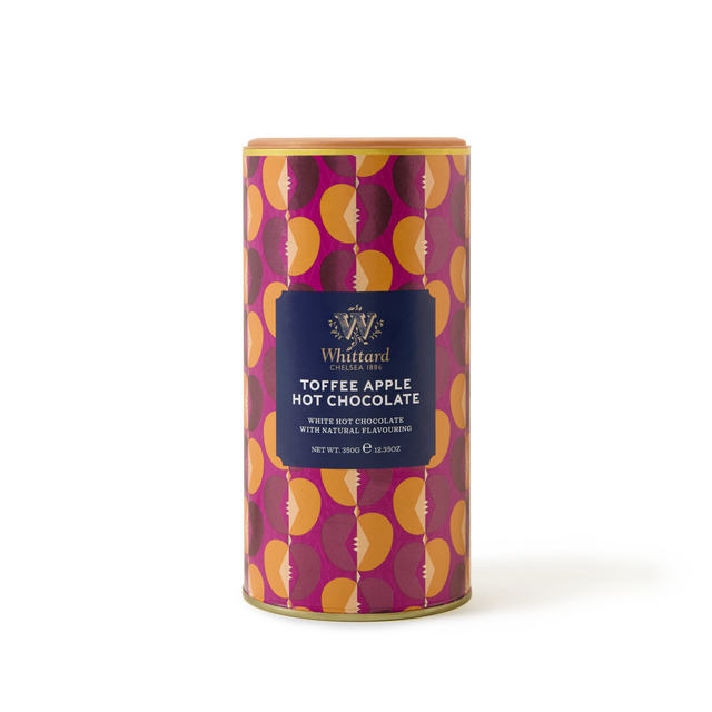 A limited edition cylindrical container of Whittard Toffee Apple White Hot Chocolate features a vibrant design with orange and pink apples and a dark blue front label, offering a unique twist on the classic hot chocolate flavor.