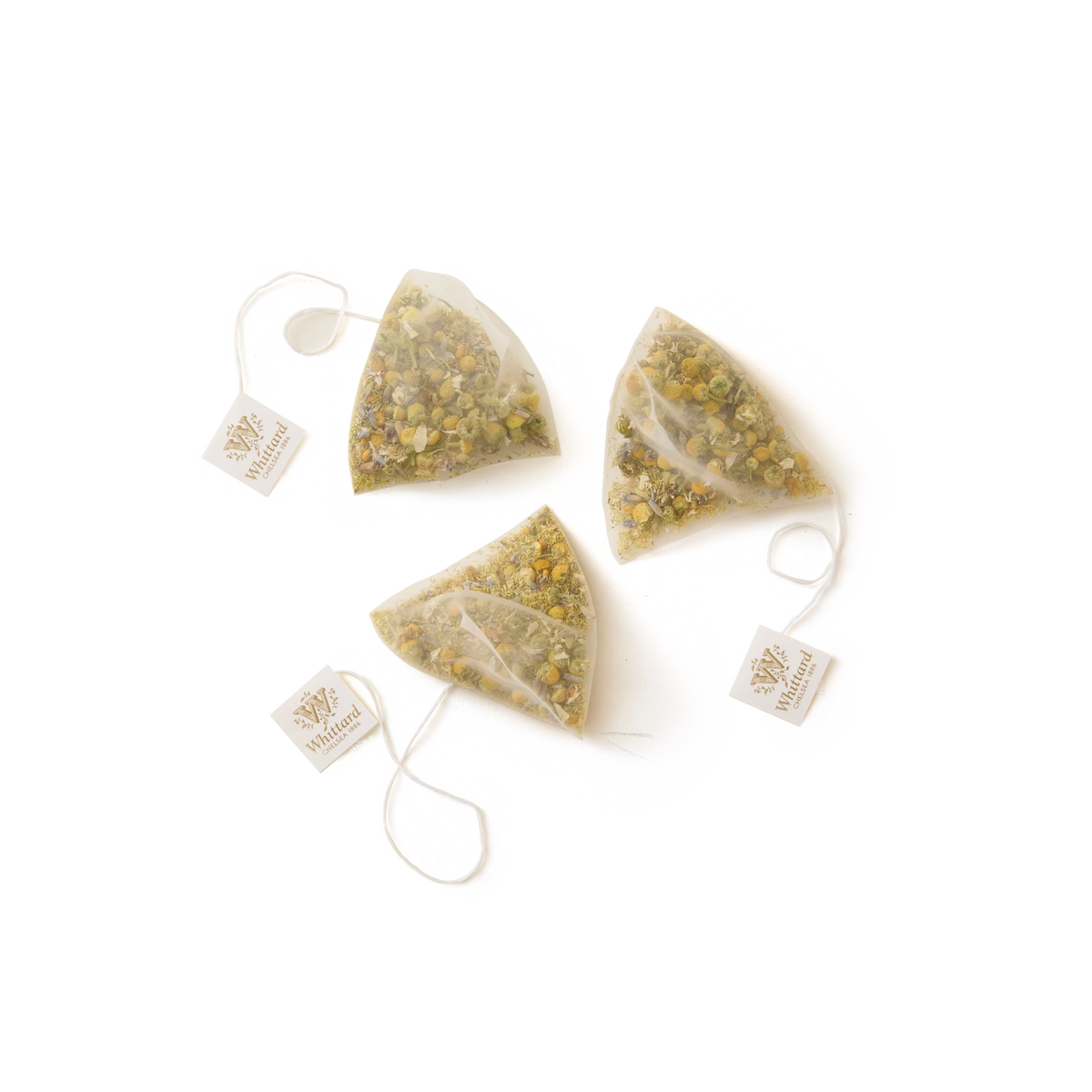 Three pyramid-shaped Camomile, Lavender and Bee Pollen teabags, each caffeine free with visible dried flowers and string tags, are placed on a white background.