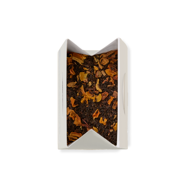 An open white pouch of POUCH SPICED PUMP CHAI 26 containing loose leaf chai with visible dried orange and brown fruit pieces, viewed from above on a white background.