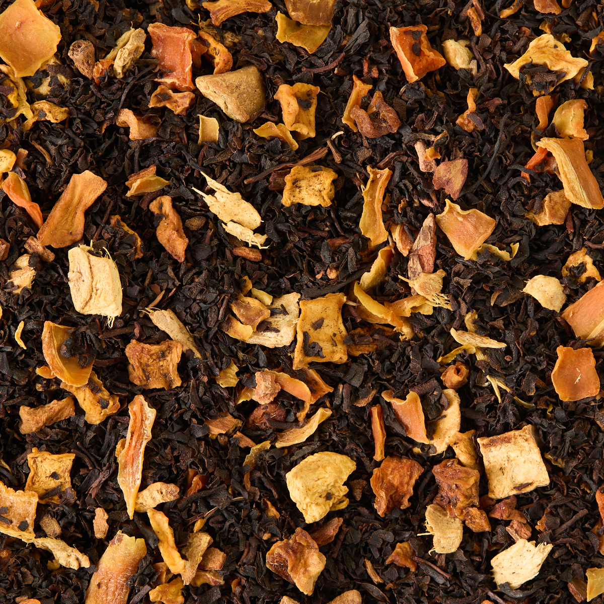 A vibrant blend of POUCH SPICED PUMP CHAI 26 loose leaf tea is scattered across a dark background, featuring dried apple chunks, cinnamon, and orange peel for an invitingly warm chai aroma.
