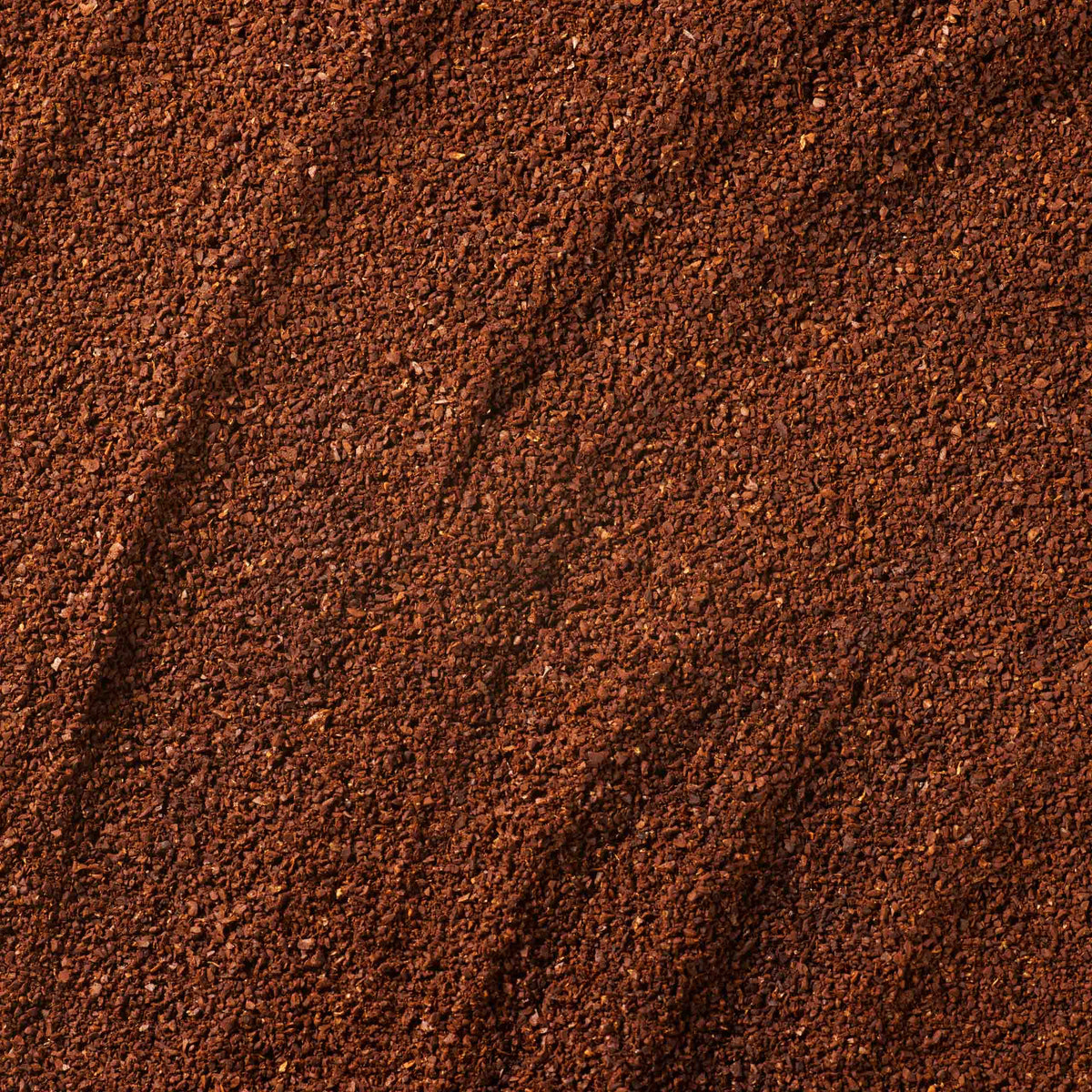 A close-up of a textured surface covered in finely ground coffee, displaying the rich brown hues and subtle granules found in our Coffees of the World Gift Set—a tempting introduction to this exceptional collection.