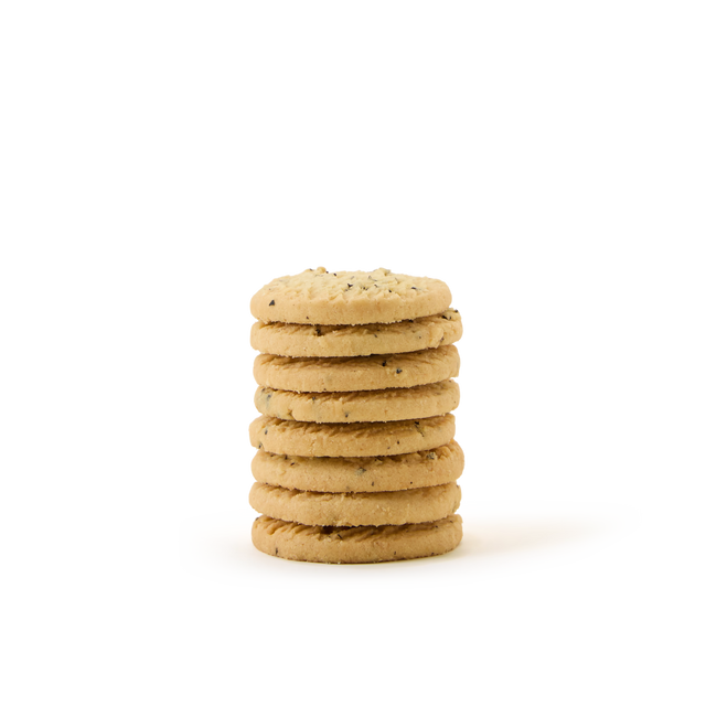 A stack of eight round, golden-brown all butter Earl Grey biscuits from the Tea Discoveries Earl Grey All Butter Biscuit Tin, featuring visible bits of seeds or nuts, sits on a plain white background—making it the perfect tea gift for any occasion.